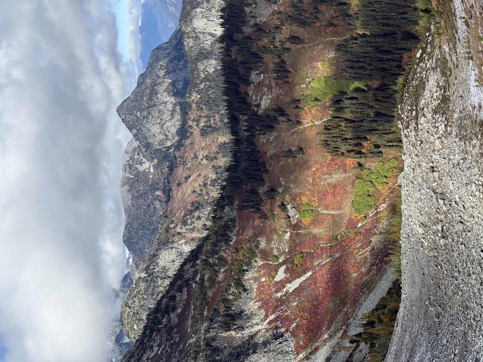 A wide basin of red and orange brush below gray peaks and talus slopes