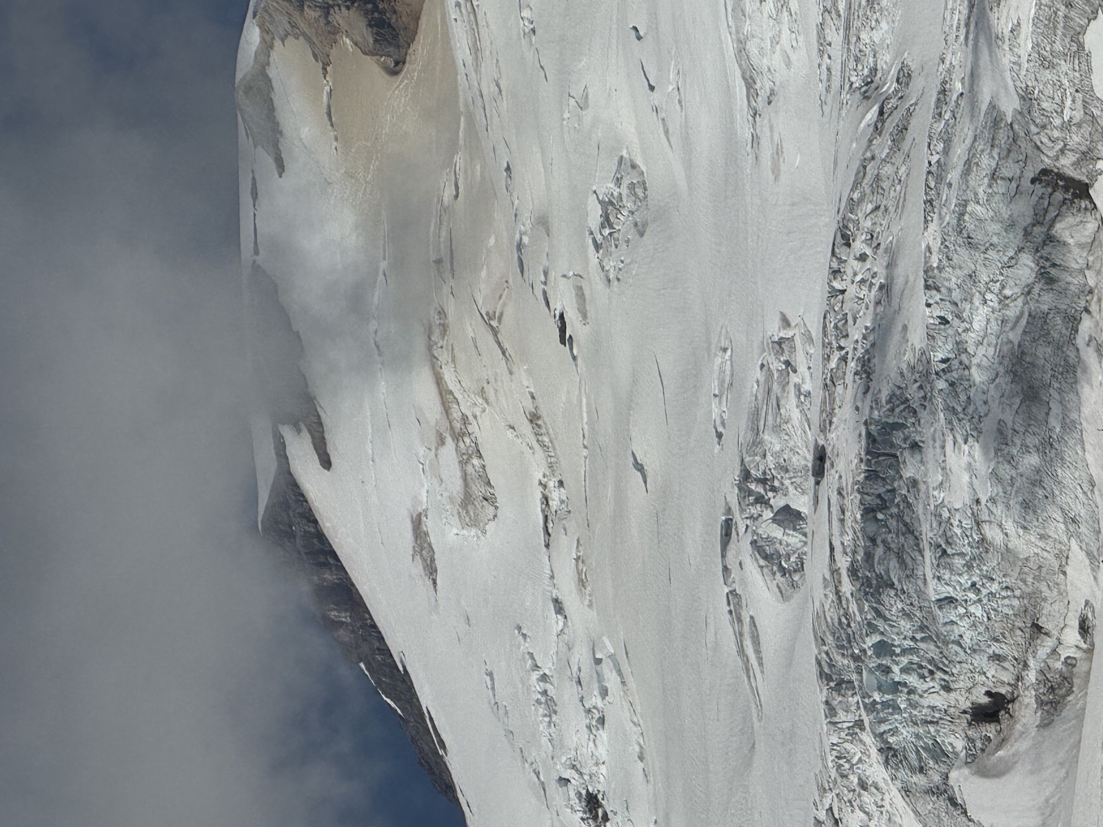 A crevassed glacier on Mount Baker with cloud drifting over the ridge above