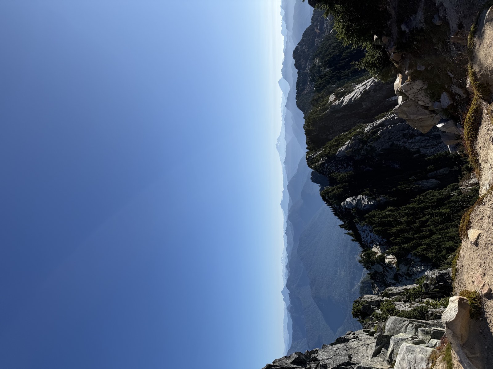 Granite crags in the foreground with layers of distant mountains under a clear sky