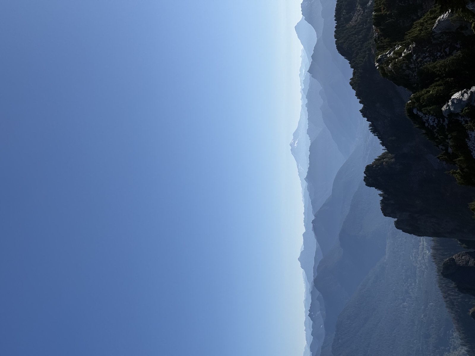 Dark rock pinnacles in the foreground and hazy blue ridges fading toward a snowy peak