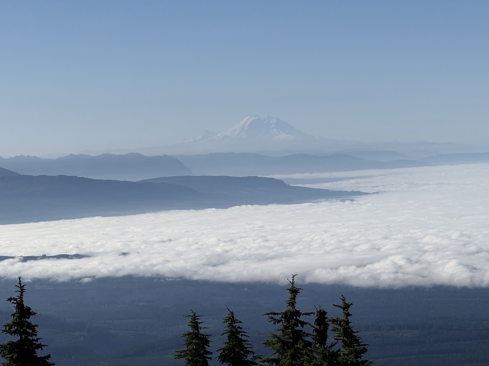 A flat layer of fog covering the lowlands, with Mount Rainier faint on the horizon