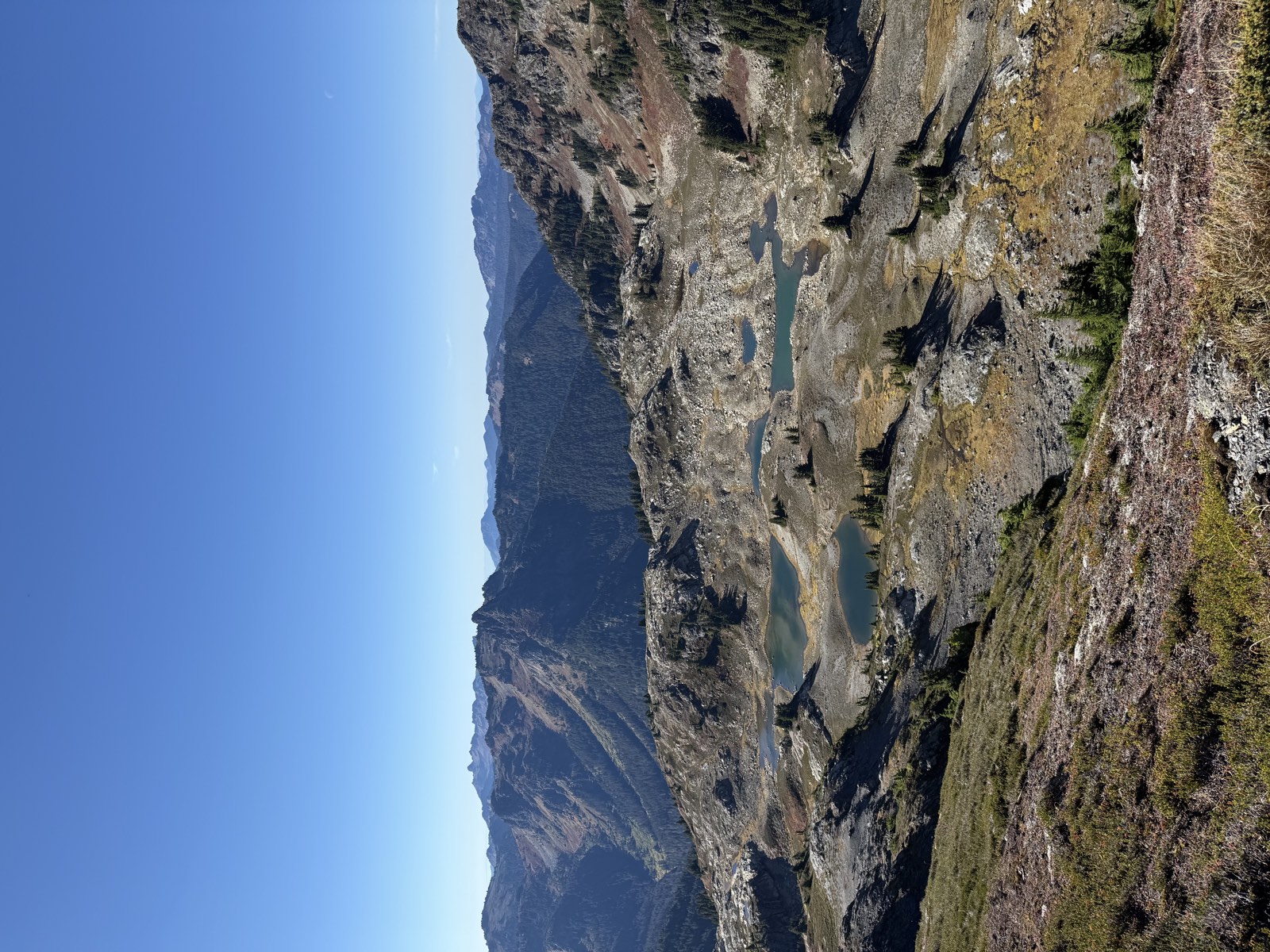 Several small blue-green tarns scattered across a rocky basin below the butte